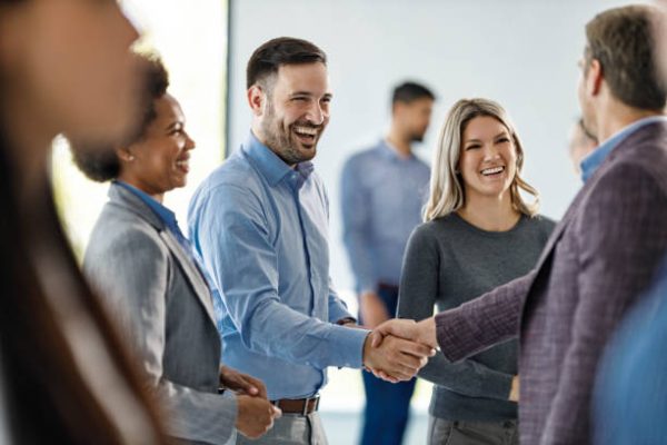 Happy male entrepreneurs came to an agreement next to their female colleagues at corporate office.